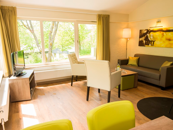 De modern ingerichte en lichte woonkamer van een bungalow op Landal Wirfttal, met een comfortabele zithoek en uitzicht naar buiten.