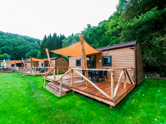 Moderne houten woodlodges met een veranda op een groen veld op Landal Wirfttal in de Eifel.