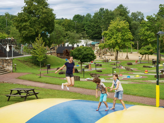 Kinderen springen en hebben plezier op de grote air-trampoline in de buitenspeeltuin van Landal Wirfttal.