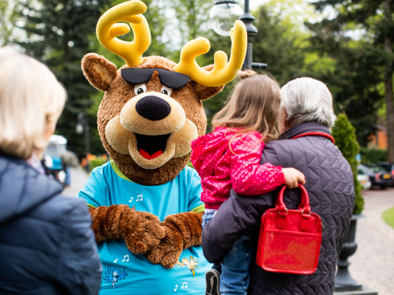 Parkmascotte Spot de eland poseert voor een foto met een meisje en haar opa en oma op Landgoed de Scheleberg.