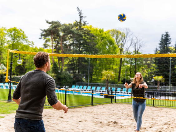 Een man en een vrouw spelen een potje beachvolleybal op het zandveld van Landgoed de Scheleberg op de Veluwe.