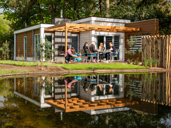Een luxe, modern vakantiehuis met een terras aan een vijver waarin het huisje perfect weerspiegelt, op Landgoed de Scheleberg.