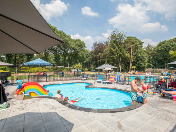 Overzicht van het aparte peuterbad met een kleurrijke regenboogglijbaan waar jonge kinderen veilig kunnen spelen in het water.