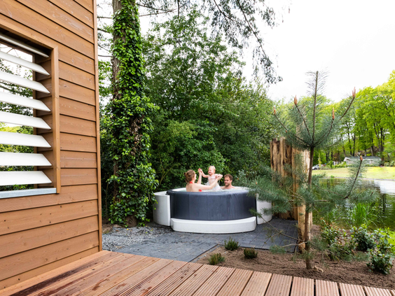 Gasten ontspannen in een privé hottub in de tuin van een wellness vakantiehuis, omgeven door de natuur van de Veluwe.
