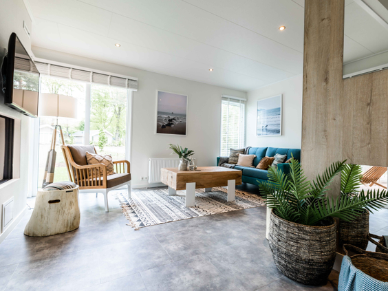 Stijlvol ingerichte woonkamer van een vakantiewoning op Landgoed de Scheleberg, met een comfortabele bank, hippe stoel en veel licht.