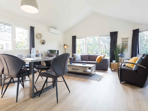 Het stijlvolle en lichte interieur van de woonkamer in een vakantiewoning op Landgoed de Scheleberg, met een eethoek en zithoek.
