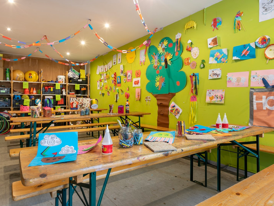 De gezellige knutselruimte van de kidsclub op Landgoed het Grote Zand, vol met knutselspullen en kindertekeningen aan de muur.