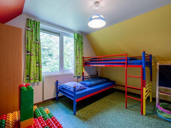 Kleurrijke kinderslaapkamer in een vakantiehuis op Landgoed Ruwinkel, met een stapelbed en grote speelblokken.