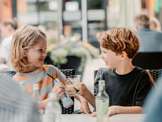 Twee kinderen proosten met limonade op het terras van de horeca op Landgoed Ruwinkel.