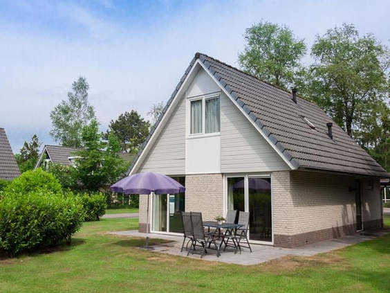 Vrijstaand vakantiehuis op Landgoed Ruwinkel met een ruime groene tuin en een terras met tuinmeubilair.