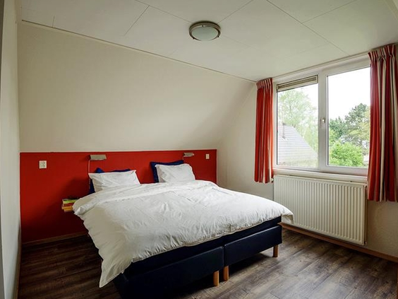 De ouderslaapkamer in een vakantiewoning op Landgoed Ruwinkel, met een netjes opgemaakt tweepersoonsbed.
