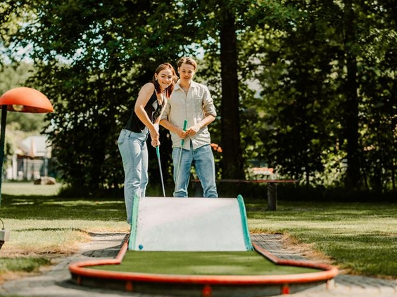 Een vader en zoon spelen geconcentreerd een potje midgetgolf op de midgetgolfbaan van Landgoed Ruwinkel.
