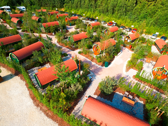 Luchtfoto van het uitgestrekte LEGOLAND Feriendorf met talloze kleurrijke gethematiseerde bungalows en huisjes, omringd door groen.