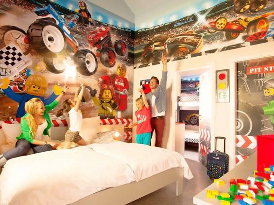 Gezin in een LEGOLAND Duitsland hotelkamer met raceauto thema, omringd door LEGO modellen en decoraties.