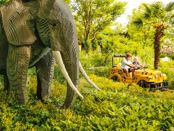 Kinderen in een safari-jeep rijden langs een levensgrote LEGO olifant tijdens de Safari Tour in LEGOLAND Duitsland.