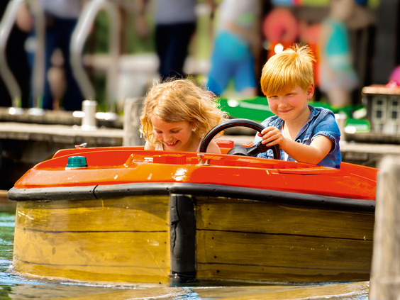 Twee blije kinderen besturen zelf een LEGO bootje tijdens de haven rondvaart in LEGOLAND Duitsland.