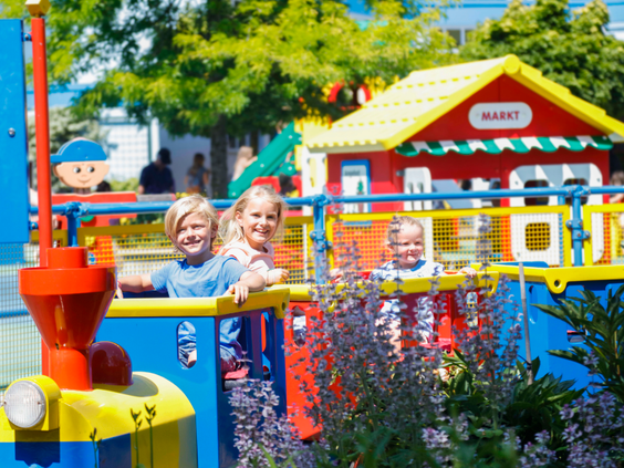Jonge kinderen zwaaien vrolijk vanuit de kleurrijke DUPLO trein in LEGOLAND Duitsland.