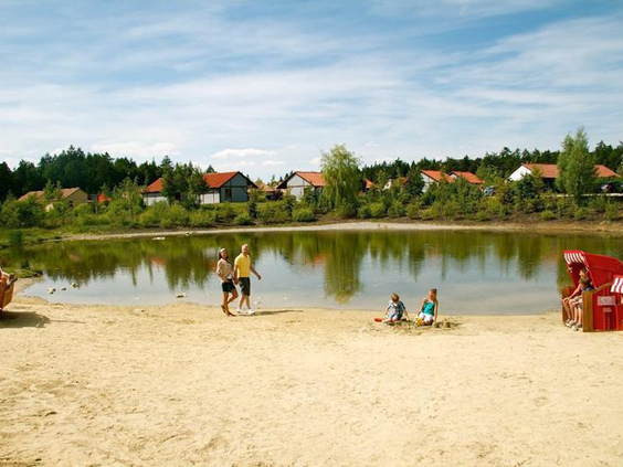 Families genieten van het zandstrand en het meer bij het LEGOLAND Feriendorf in Beieren, ideaal voor ontspanning en waterpret.