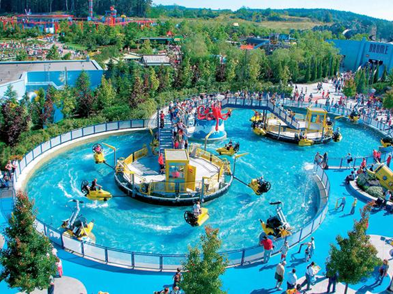Kinderen en volwassenen in ronde bootjes op een draaiende waterattractie, met waterkanonnen en sproeiers in LEGOLAND Deutschland.
