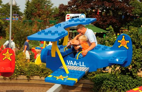 Vader en kind in de attractie DUPLO® Plane in LEGOLAND® Billund, waarbij ze zelf de hoogte van het vliegtuig besturen.