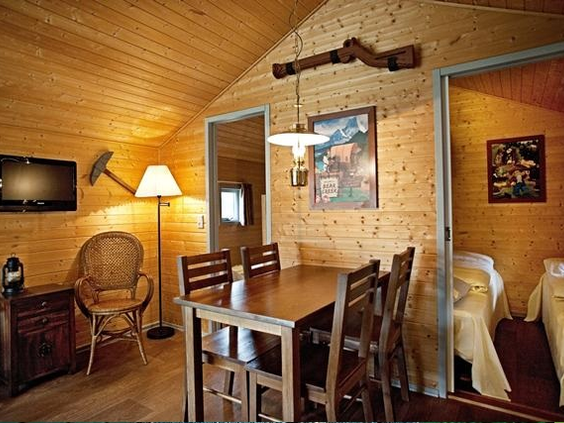 De gezellige, houten woonkamer van een Wild West Cabin in LEGOLAND Holiday Village, met een eettafel en zithoek.