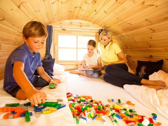 Een gezin dat gezellig samen met LEGO speelt in een Wilderness Camping Barrel bij LEGOLAND Holiday Village.