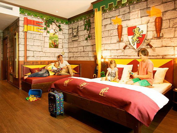 Een ruime familiekamer in ridder-thema in het LEGOLAND kasteelhotel, met een tweepersoonsbed en een apart stapelbed voor de kinderen.