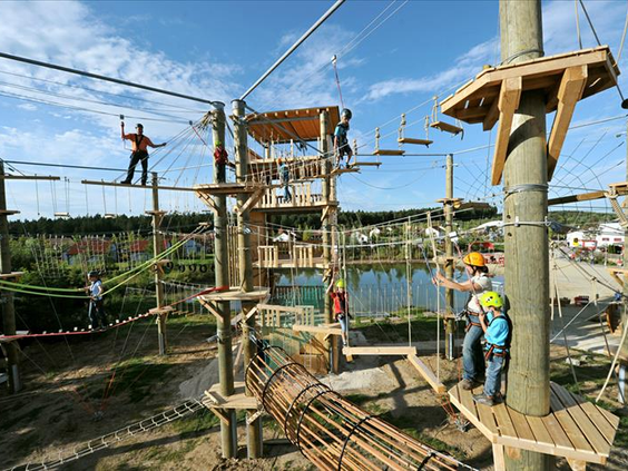 Kinderen en volwassenen klimmen op het uitdagende hoogteparcours met touwbruggen en hindernissen in het LEGOLAND Feriendorf in Duitsland.