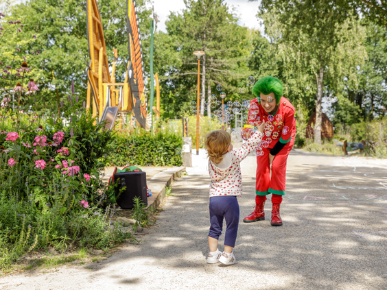 Een klein kindje geeft een high five aan de vrolijke, rode mascotte Orry in het vakantiepark Center Parcs Limburgse Peel.