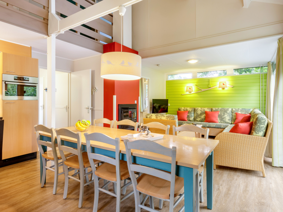 Het kleurrijke interieur van een vakantiecottage in Center Parcs Limburgse Peel, met een ruime eettafel en een opvallende groene keuken.