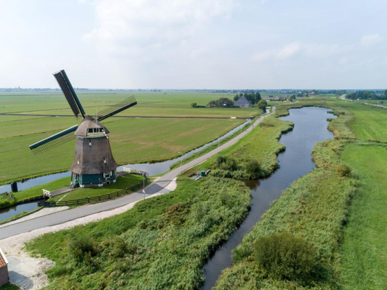 Een typisch Hollands polderlandschap met een klassieke windmolen en een sloot in de groene omgeving van Volendam.