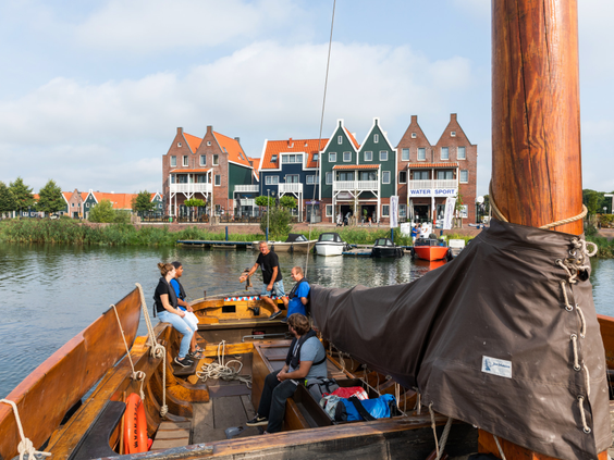 Gezinnen genieten van een rondvaart op een traditionele Volendamse boot, met uitzicht op de kleurrijke huisjes van Marinapark Volendam.