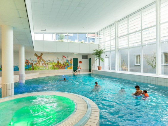 Het overdekte zwembad van Marinapark Volendam met een heerlijk bubbelbad en gezinnen die genieten van het water.