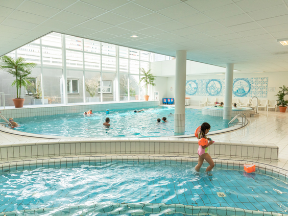 Een meisje stapt voorzichtig in het ondiepe peuterbad van het binnenzwembad bij Marinapark Volendam.