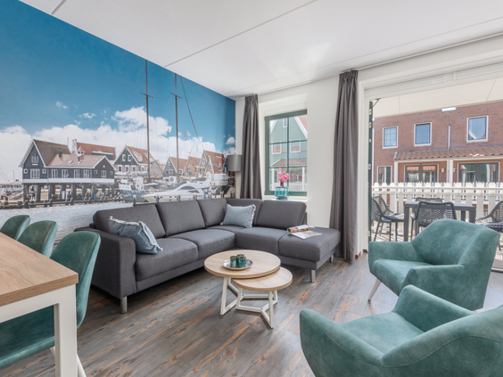 De sfeervolle woonkamer van een vakantiehuis op Marinapark Volendam, met een grote fotowand van de Volendamse haven.