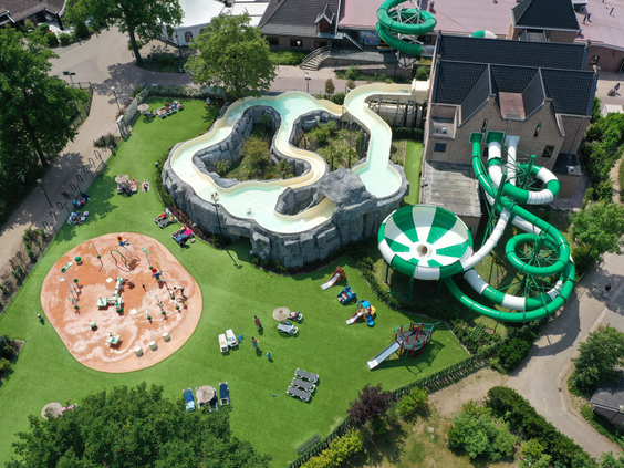 Luchtfoto van het grote buitenzwembad en waterpark van Marveld Recreatie met diverse waterglijbanen en een wildwaterbaan.