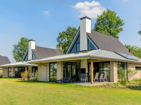 Moderne, luxe vakantiehuizen met grote ramen en een ruim grasveld ervoor op vakantiepark Marveld Recreatie.