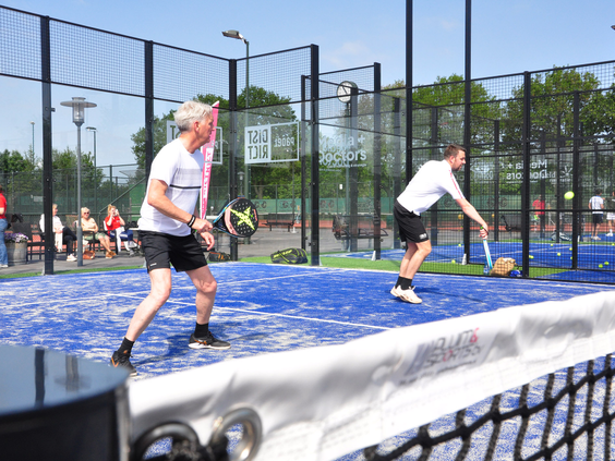 Twee mannen zijn fanatiek aan het padellen op de blauwe padelbaan van Marveld Recreatie.