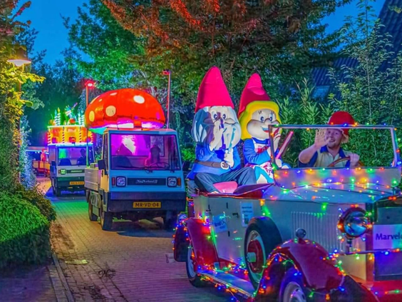 De kleurrijk verlichte wagens van de avondparade met mascottes rijden in het donker over vakantiepark Marveld Recreatie.