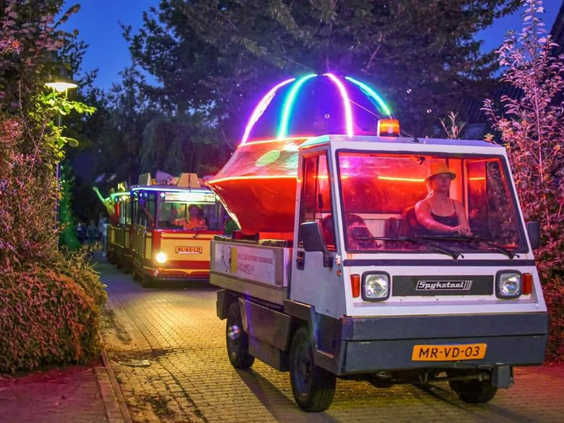 Kleurrijke voertuigen rijden in een verlichte parade bij Marveld Recreatie