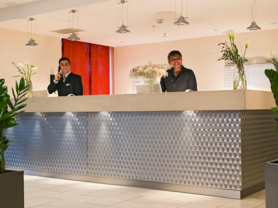 De moderne receptie van het kindvriendelijke Mercure Hotel Duisburg City, waar het personeel klaarstaat om gezinnen te verwelkomen.