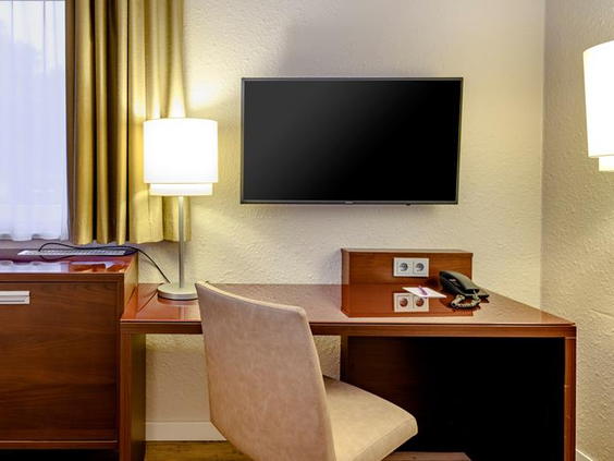 De hotelkamer in Mercure Duisburg met een flatscreen TV en een bureau, handig voor het uitstippelen van familie-uitstapjes.