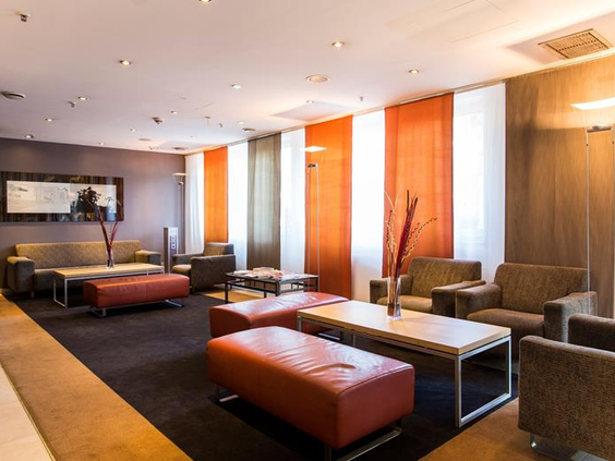 De sfeervolle lounge van het Mercure Hotel in Duisburg met comfortabele banken en oranje accenten, een fijne plek om als gezin te zitten.