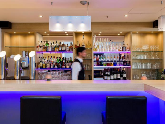 De stijlvolle hotelbar van het Mercure Hotel in Duisburg, met sfeervolle blauwe verlichting en een ruime keuze aan drankjes.