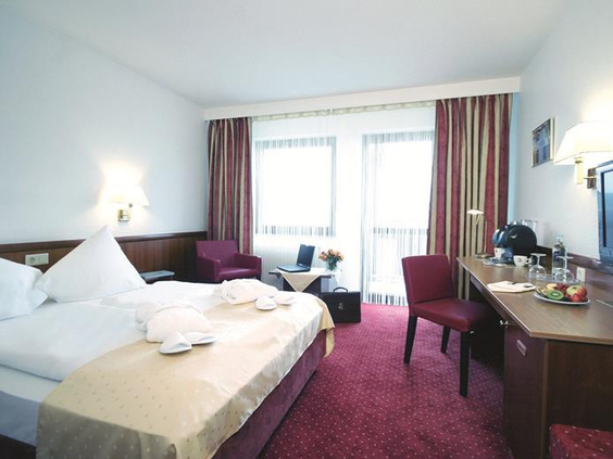 Een nette en comfortabele hotelkamer in het Mercure Hotel Bad Dürkheim, met een opgemaakt bed en een bureau, ideaal voor een gezin.