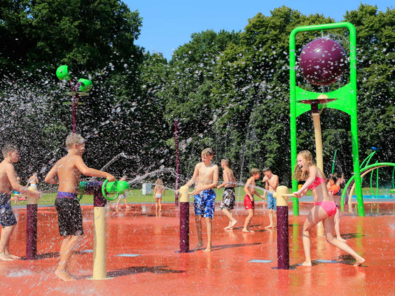 Kinderen hebben een watergevecht met waterkanonnen en fonteinen in het interactieve spray-park van Waterspeelpark Splesj.