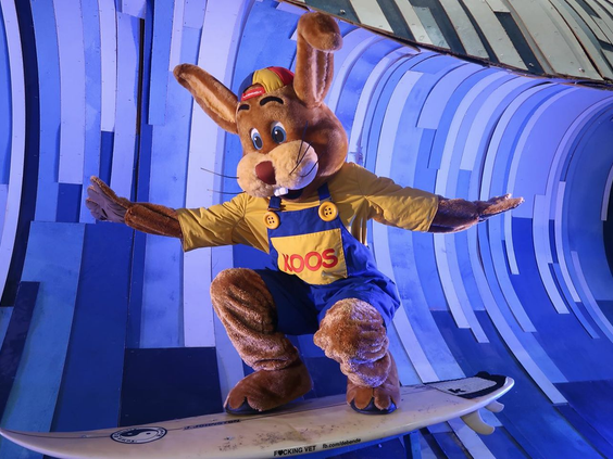 Mascotte Koos Konijn die stoer balanceert op een surfplank bij Noordzee Résidence De Banjaard.