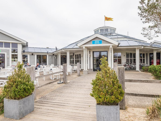 Het centrale gebouw van Noordzee Résidence De Banjaard met de brasserie en een zonnig terras.