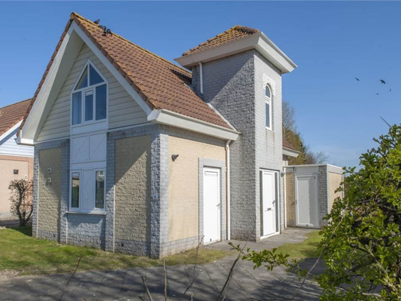 De buitenkant van een luxe, vrijstaande vakantievilla met een torentje op Noordzee Résidence De Banjaard.