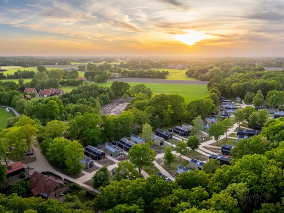 Luchtfoto van vakantiepark Olde Kottink in Overijssel bij zonsondergang, prachtig gelegen in het groene Twentse landschap.